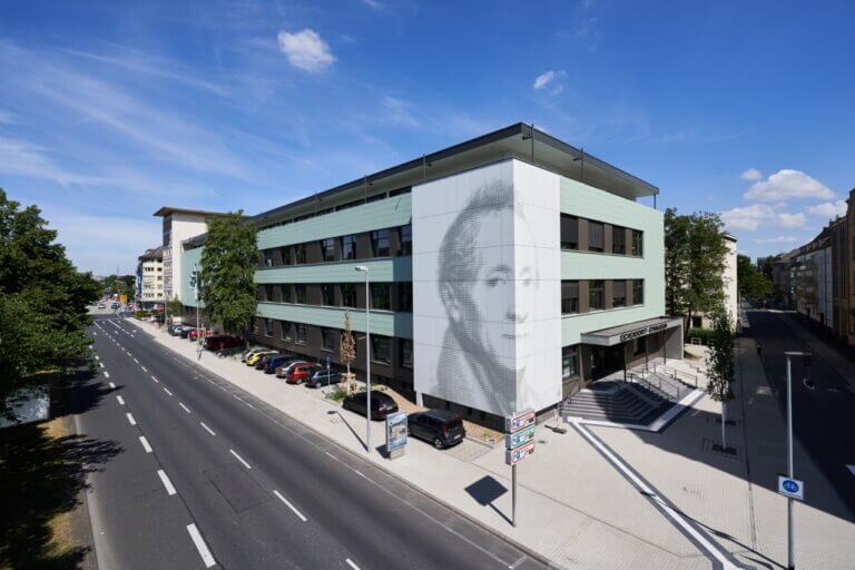 Grau-blaues Gebäude an einer Straße mit einem Gesicht auf der Fassade