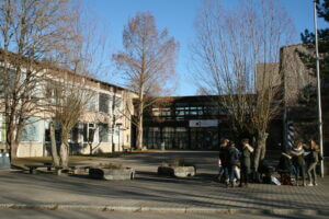 Schulgebäude mit Pausenhof und blauem Himmel